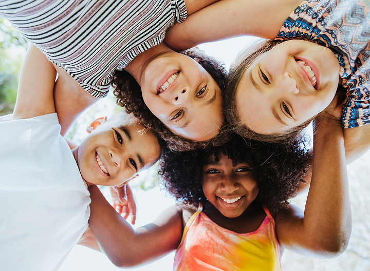 Group Of Smiling Children In A Circle Looking Down