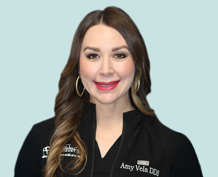 Portrait Of Dr Amy Vela In Front Of A Light Teal Background